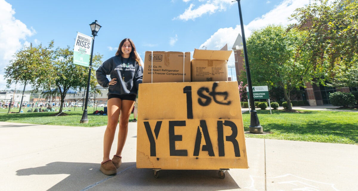 A student stops for a photo while moving in to her residence hall at Marshall University