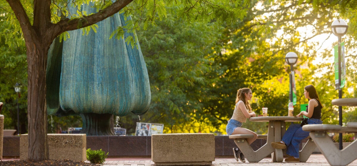 Two students sit together and enjoy coffee on the student center plaza of Marshall's Huntington campus
