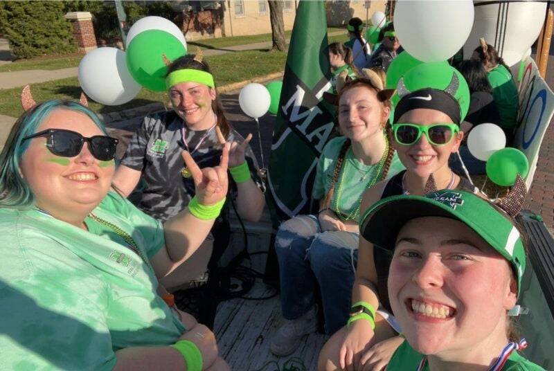 Marshall University RHA students smile together from their homecoming parade float.