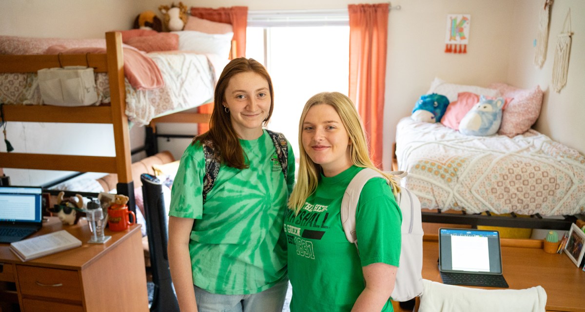 Two students smile together in their decorated dorm room