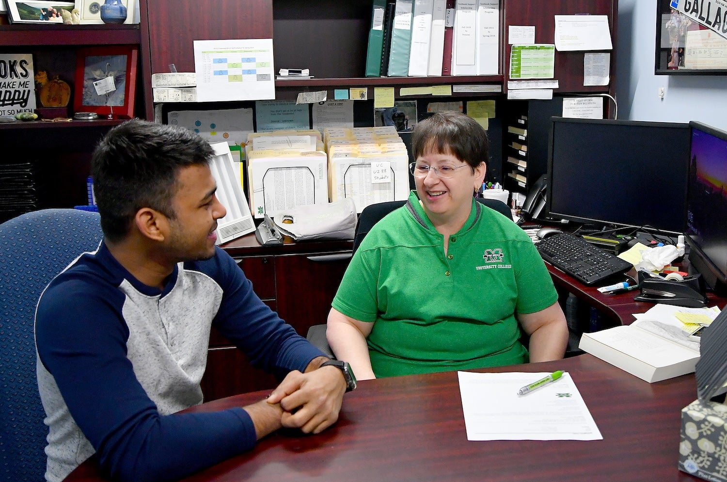 advisor talking to a student at a desk