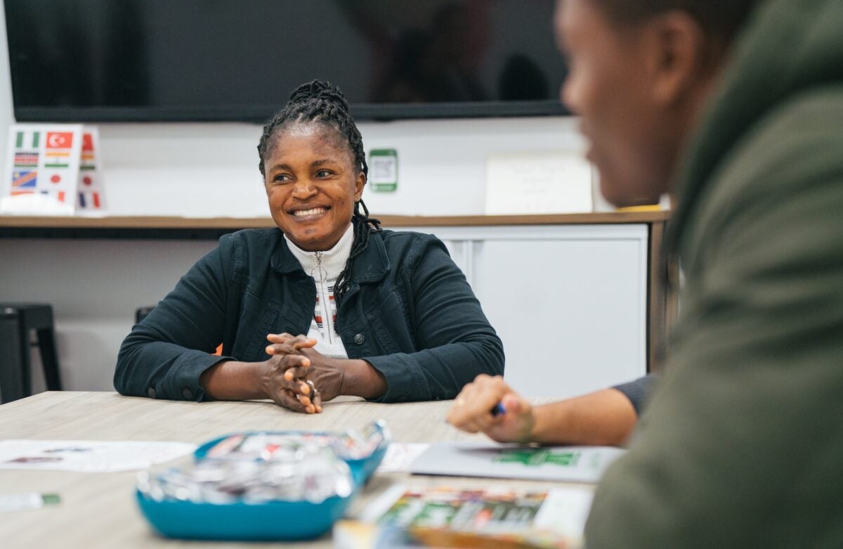 two students talking at a table in the international student center