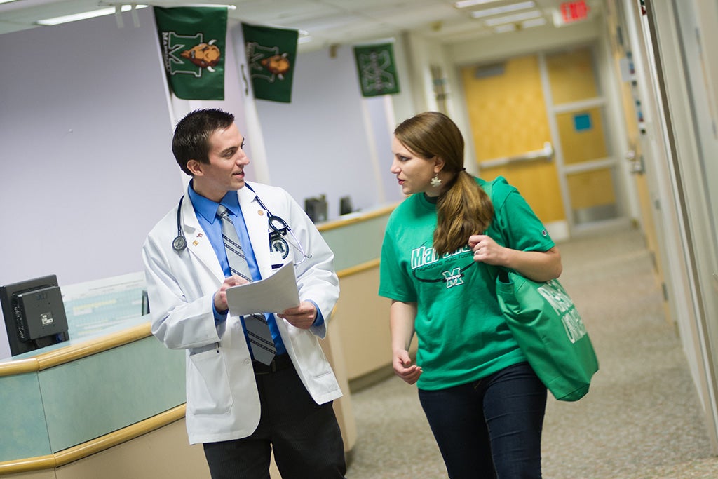 Doctor walking down the hallway with Marshall Student