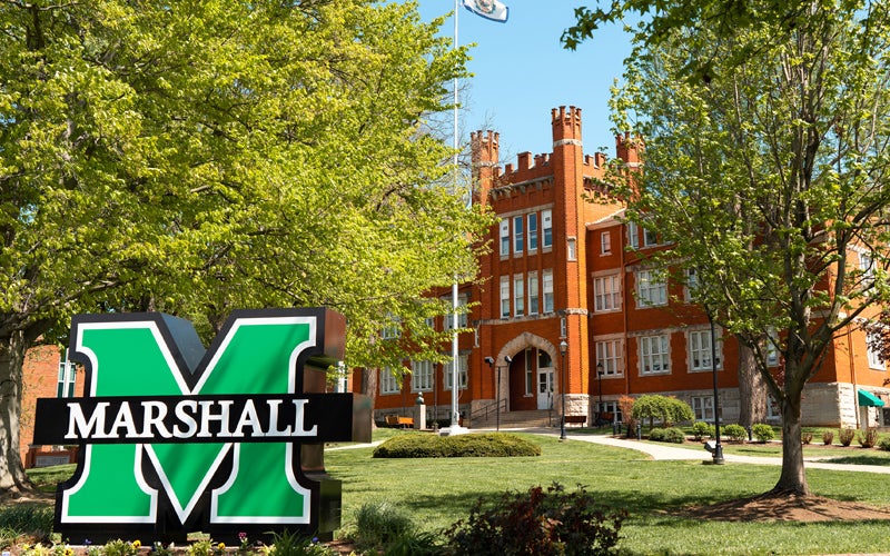 Marshall University's Old Main, a large brick building with a green Marshall sign in the front lawn