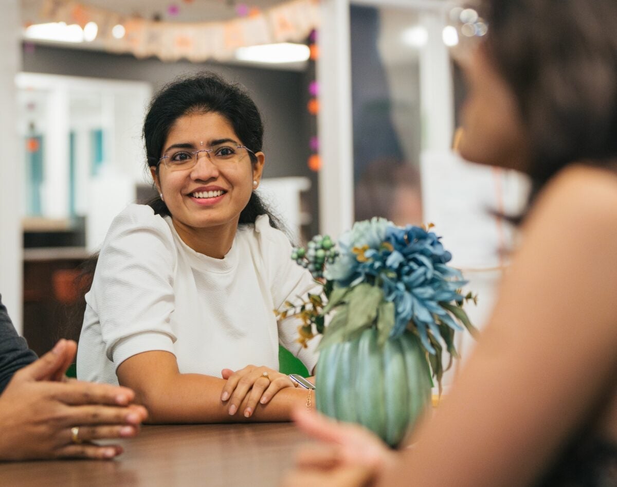 three students talking at a table with a flower on the table