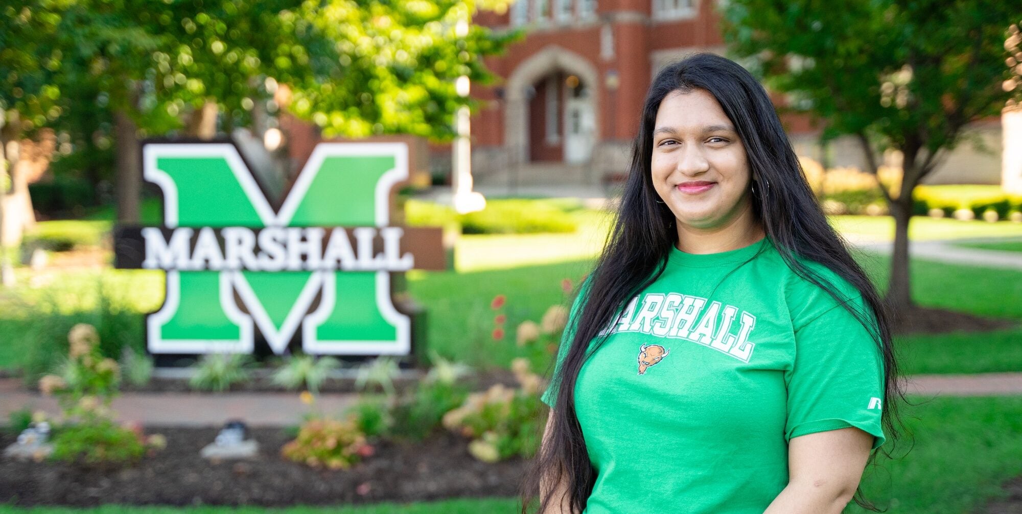 student on campus smiling at the camera in front of the block M