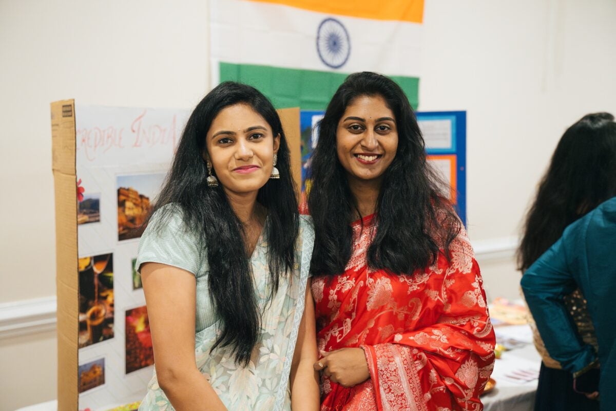 two female students posing in front of a poster board at the international festival