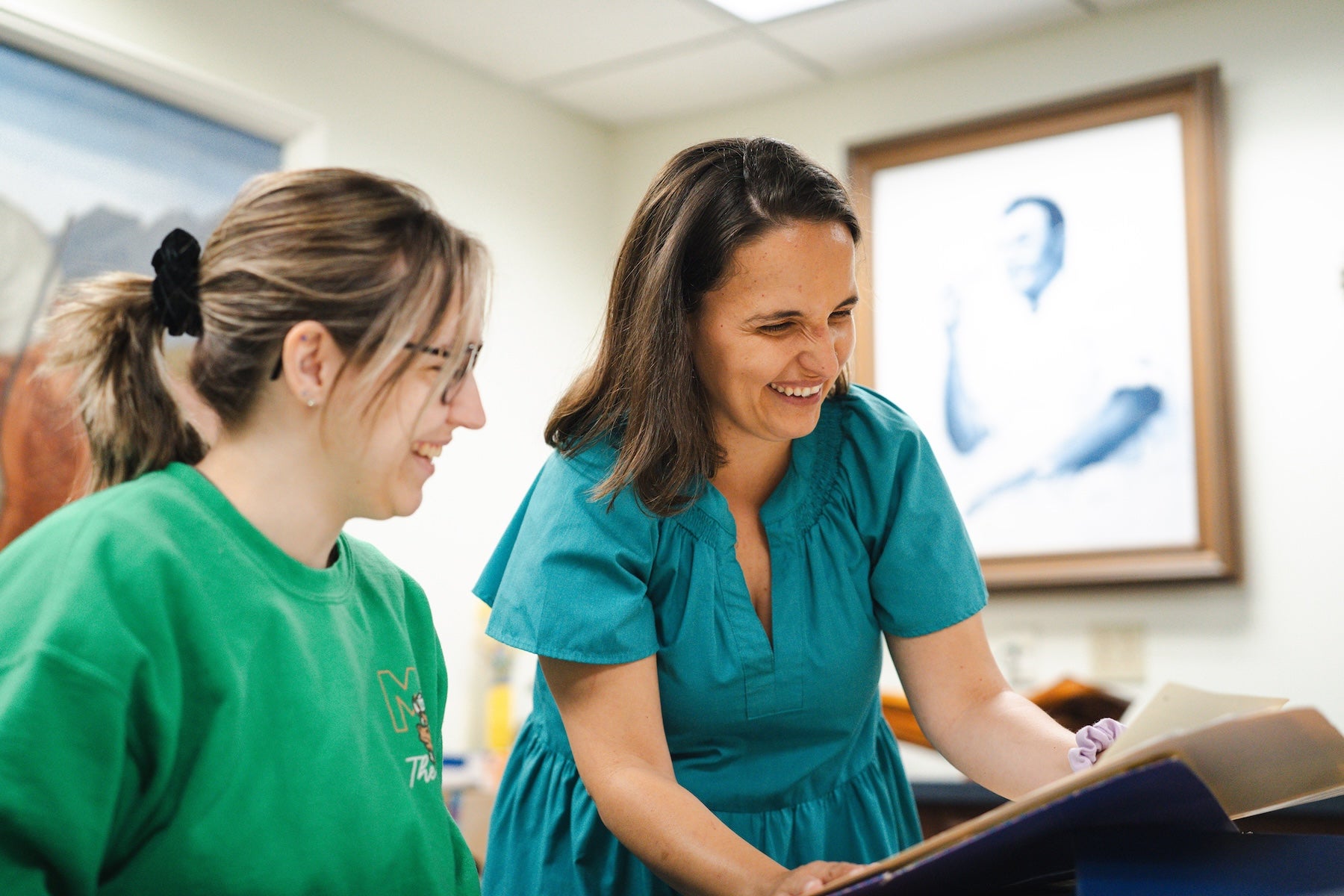 faculty member showing student a book in the library