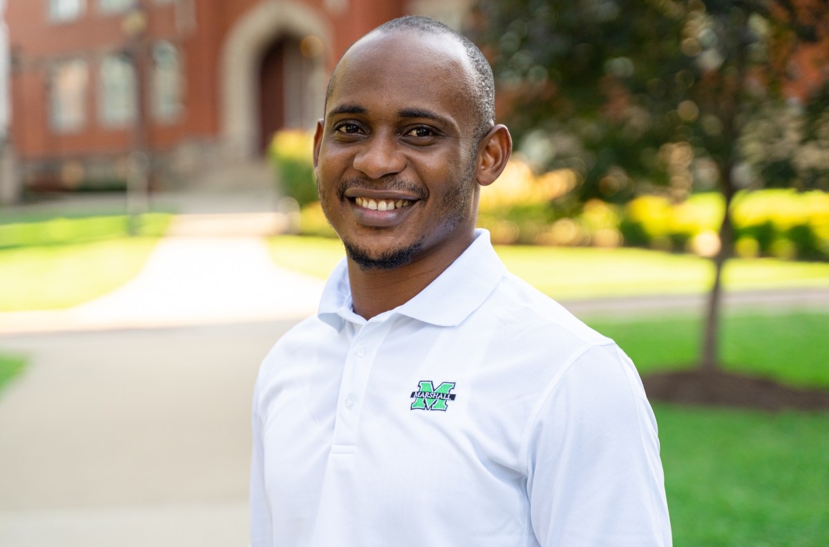 student outside Old Main on campus, smiling at the camera