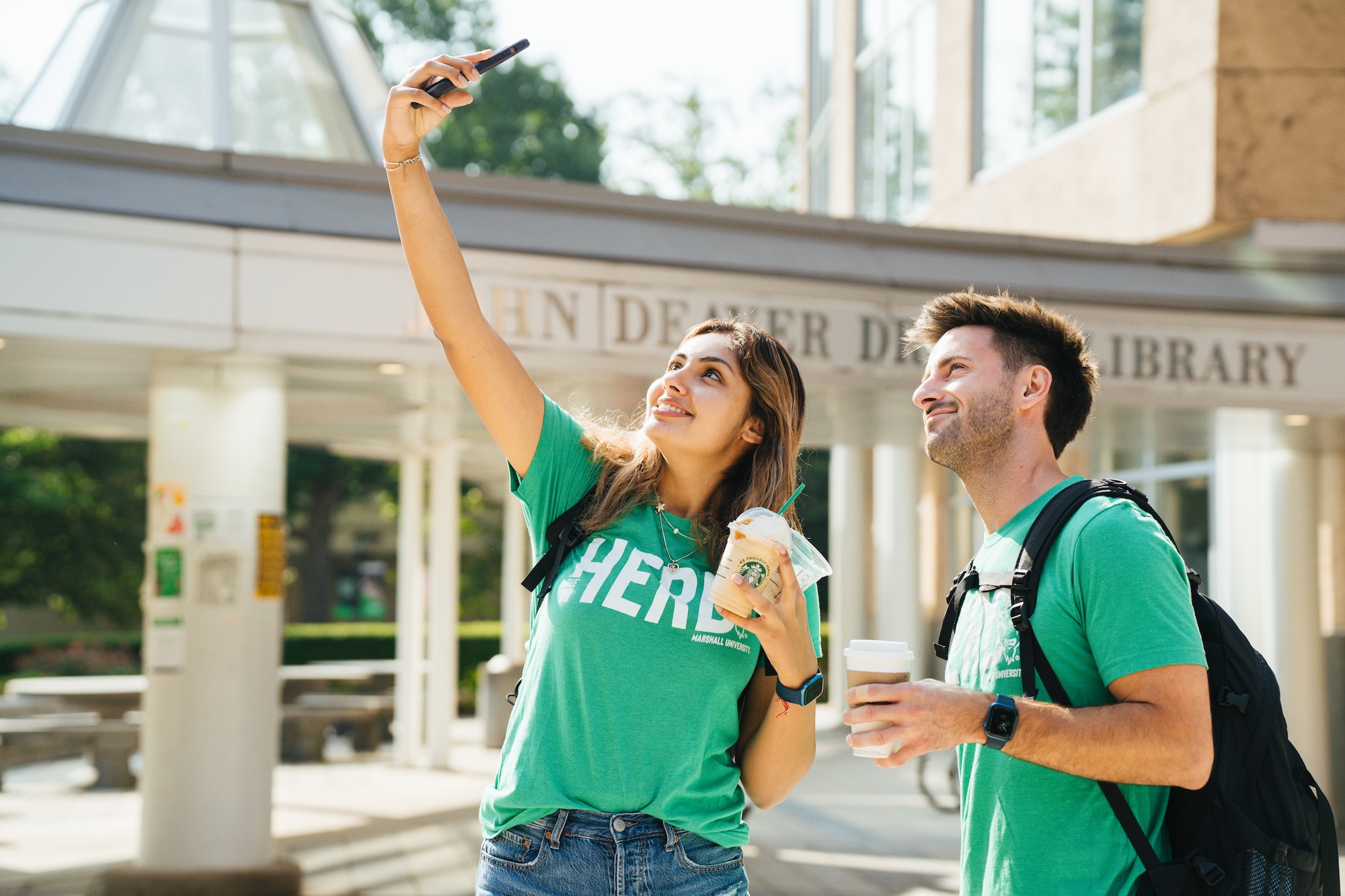 two students outside the library taking a selfie