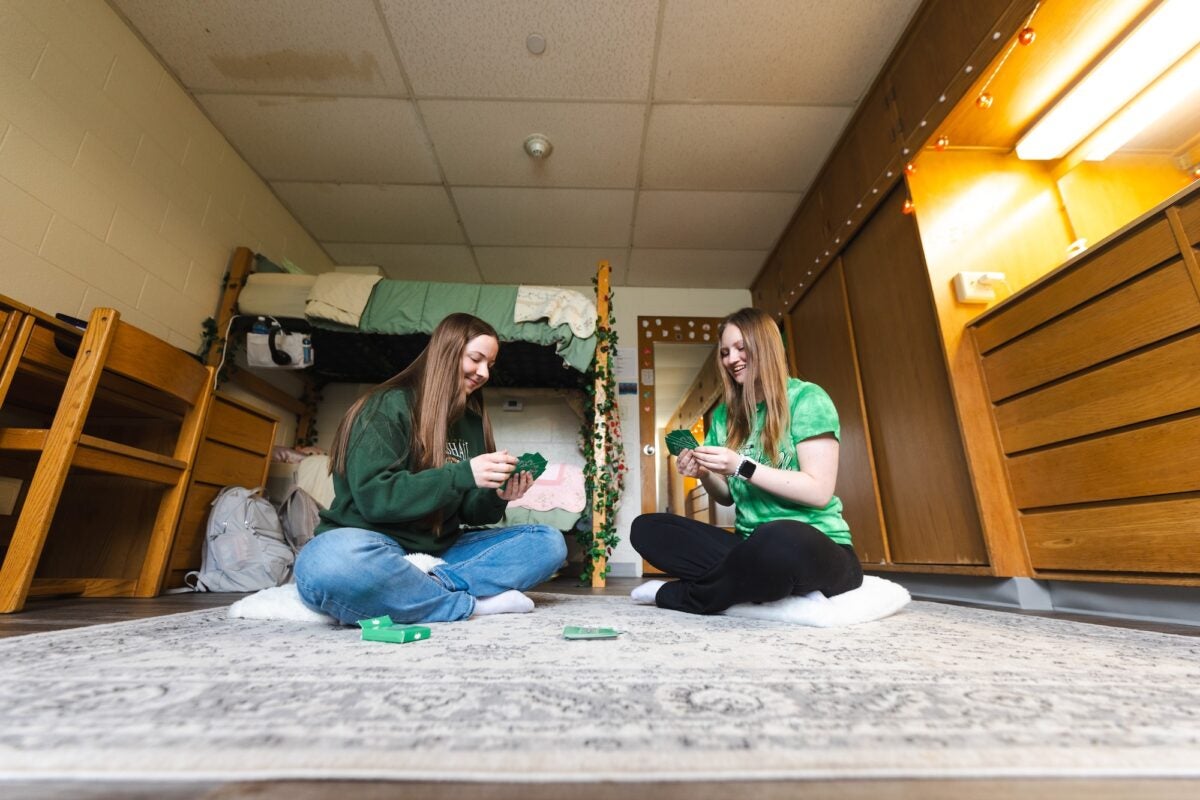 two students playing cards on the floor of a residence hall