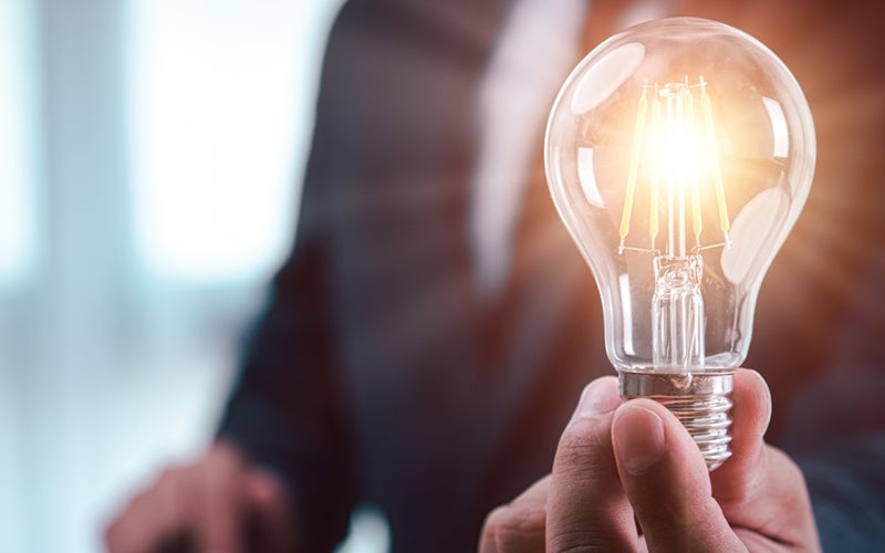 Image of a person in a suit holding a light bulb