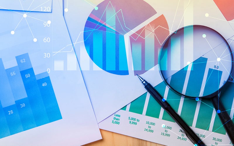 Image showing pages of graphs stacks on top of one another with a pen and magnifying glass on top