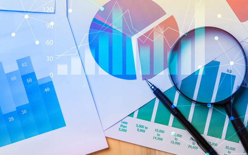 Image showing pages of graphs stacks on top of one another with a pen and magnifying glass on top