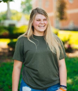 Skyla Hilliard smiles and looks off to the right while standing on Marshall University's campus