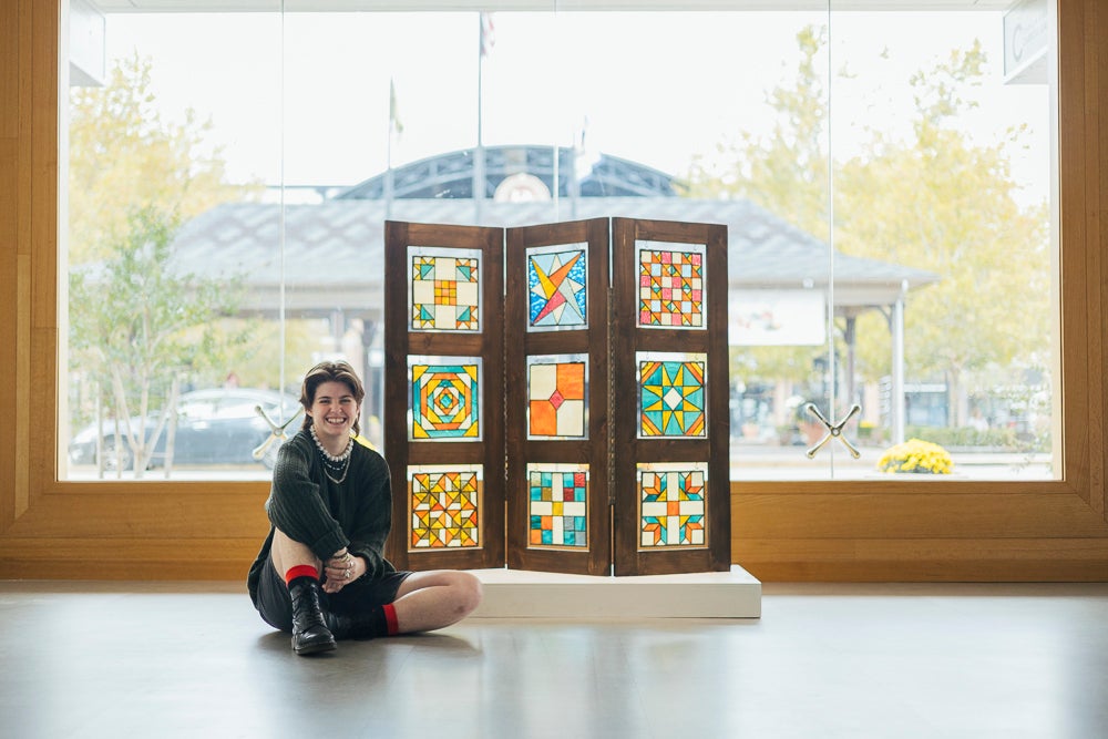 Callie Thacker with her sculpture, the Stitch of a Quilt on a Barn in Appalachia