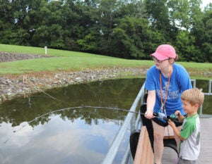 Lauren Barr helps a child fish at camp
