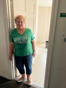 Charlotte leans against the door frame of her old dorm room in Laidley Hall at Marshall University 