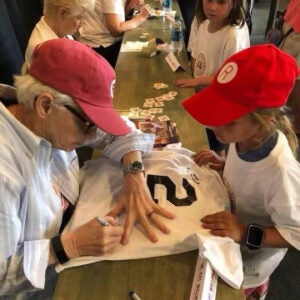 Dr. Kat Williams signs a baseball jersey for a young girl