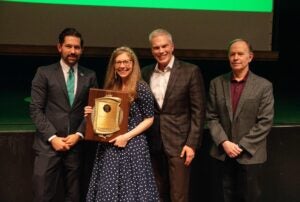 Laura Michele Diener receiving award from three people at faculty senate meeting