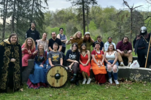 Diener's class dressed up in Viking apparel for event, about 15 students sitting outside in nature