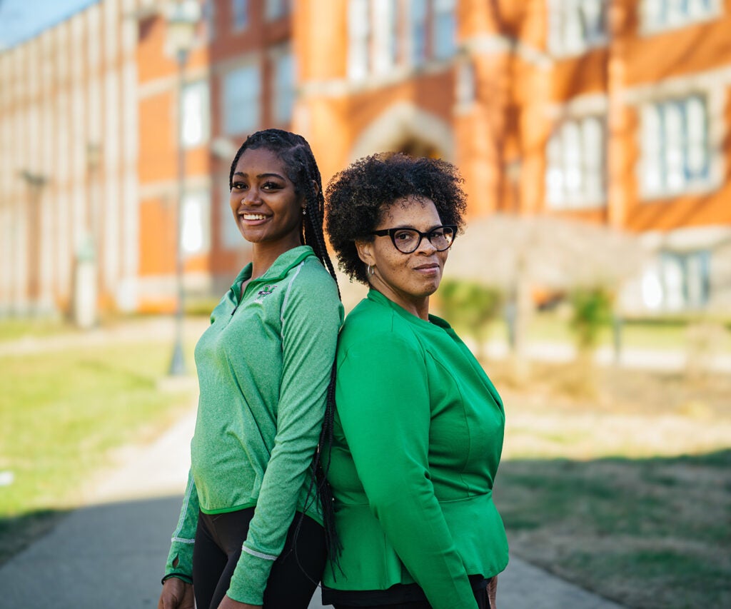 Kymora and Cassandra Woods stand back-to-back in front of Old Main at Marshall University