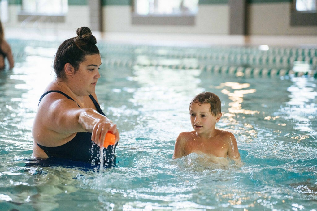 Marshall grad student Gianna Petrella helps a student learn to swim