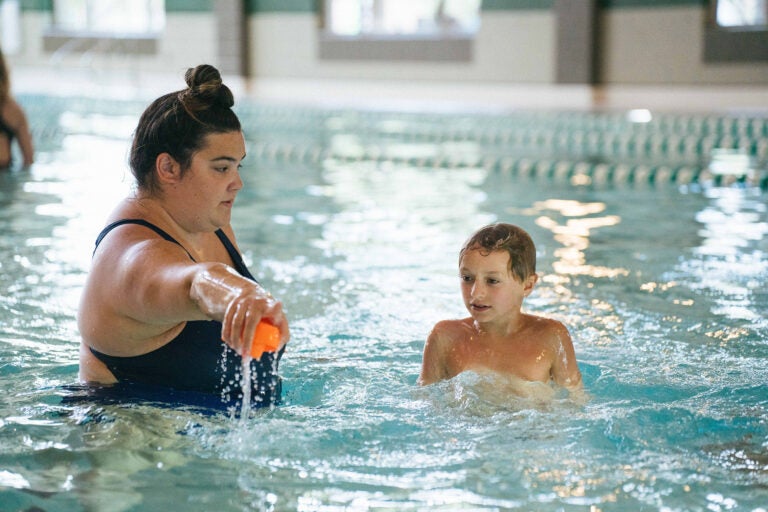 Marshall grad student Gianna Petrella helps a student learn to swim