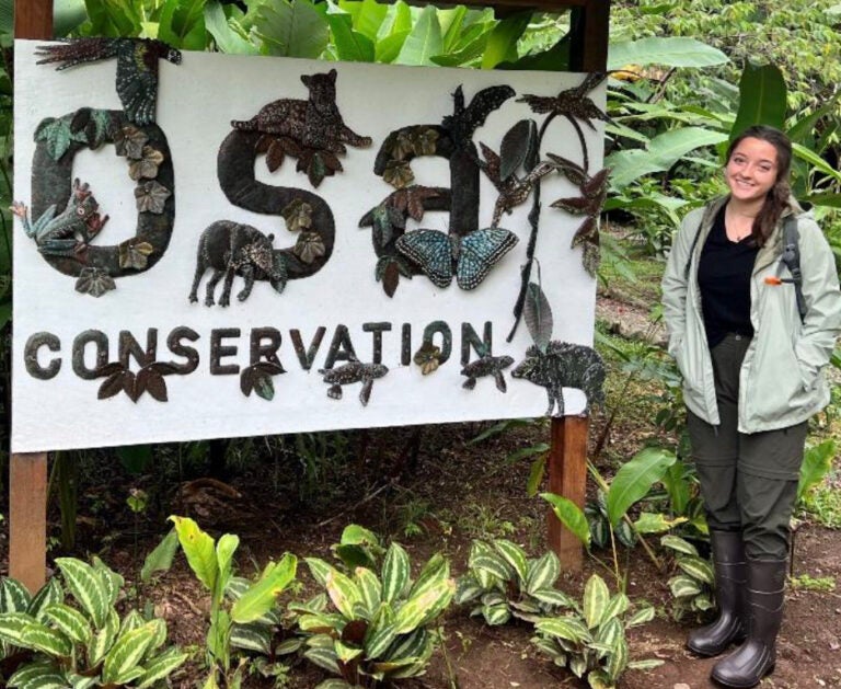 Maggie Dickerson smiles near a sign at OSA Conservation