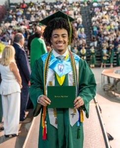 Tristan Hornbuckle smiles with his high school diploma at Huntington High's 2025 commencement ceremony.