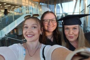 Sarah and Jackie Wazelle and their mom Nichole in a graduation cap