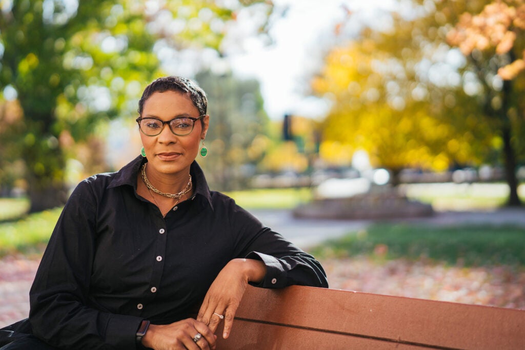 Andrea Gray sits on a bench surrounded by fall colors on Marshall University's Huntington campus