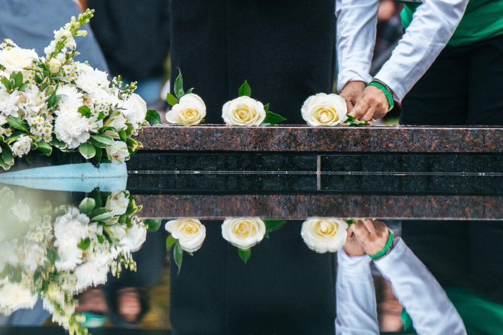 hands laying roses on the edge of the Memorial Fountain