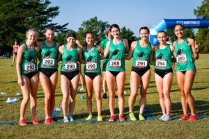 Marshall University cross country runners smile together for a photo while in their running uniforms 