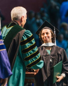 Michaela Marshall shakes Marshall President, Brad D. Smith's had during her commencement ceremony