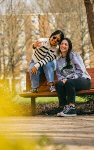 Gracie takes a selfie with a friend from a bench on Marshall University's campus