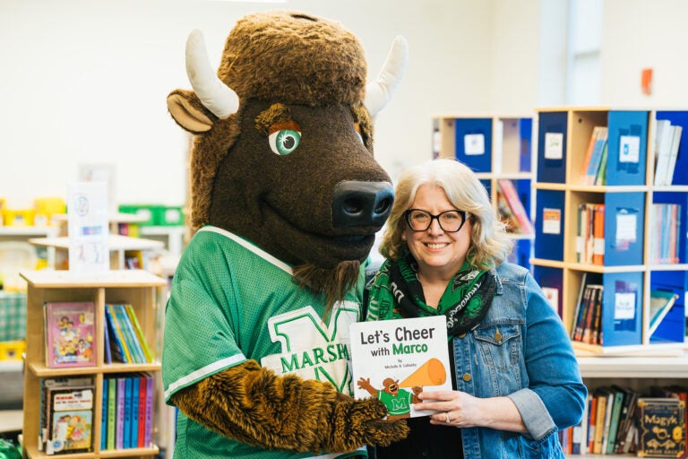 Michelle D. Callanta smiles with Marco while holding her book, Let's Cheer with Marco