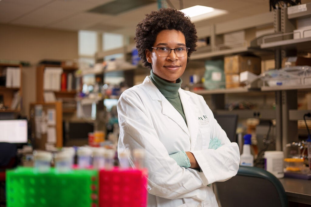 Sidney Strause stands in a lab wearing her white coat with her arms crossed