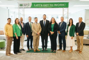 A group of community leaders gather together under a Marshall University banner that says Let's Get to Work during an economic and workforce development meeting