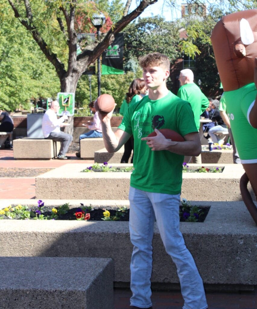 Jakob Tipton throws a football on Marshall University's Memorial Student Center Plaza