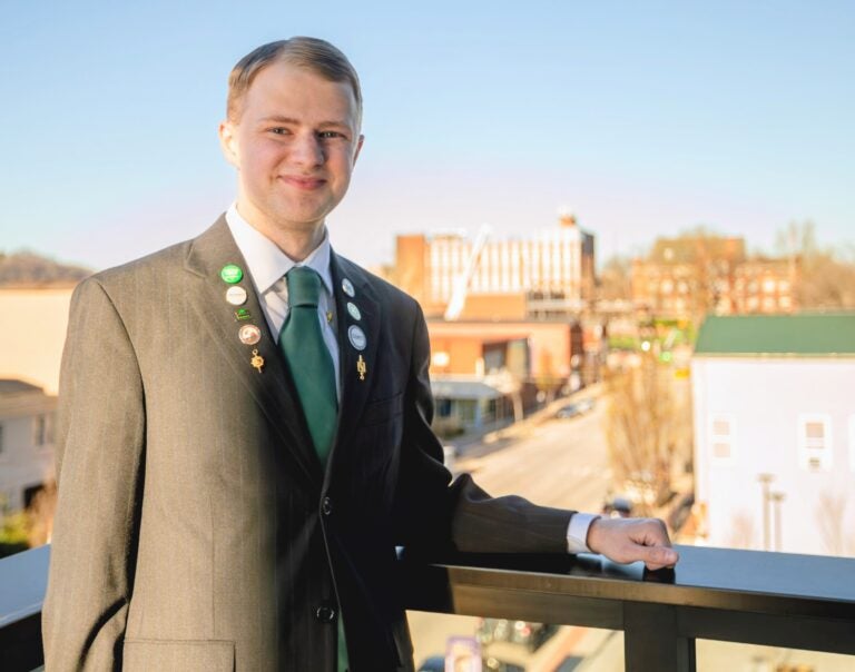 Jamison Lewis wears a suit with multiple pins on it and smiles at the camera from the Lewis College of Business Hall of Fame event.