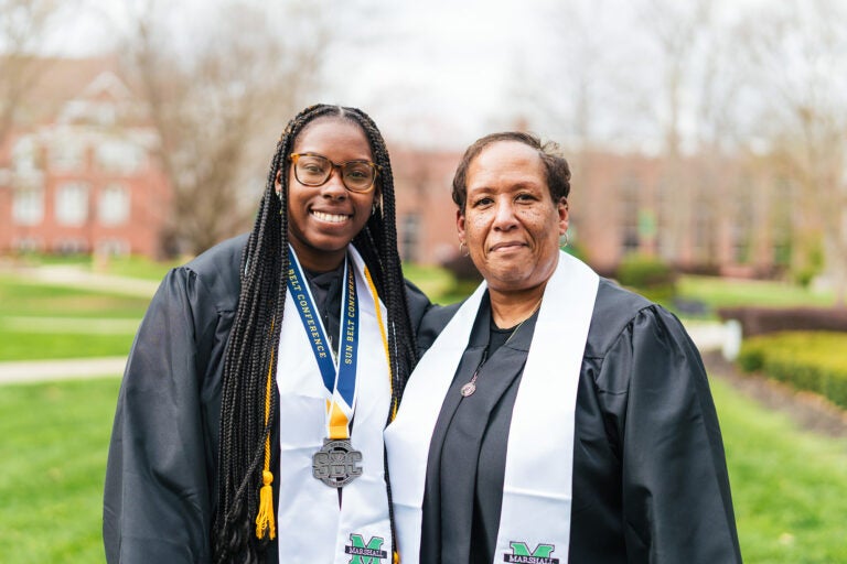 Markayla Moore and Toni Wooding smile together in their graduation regalia