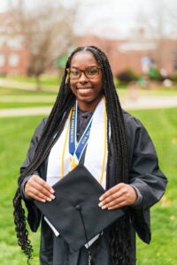 Markayla Moore wears her graduation regalia while standing outside