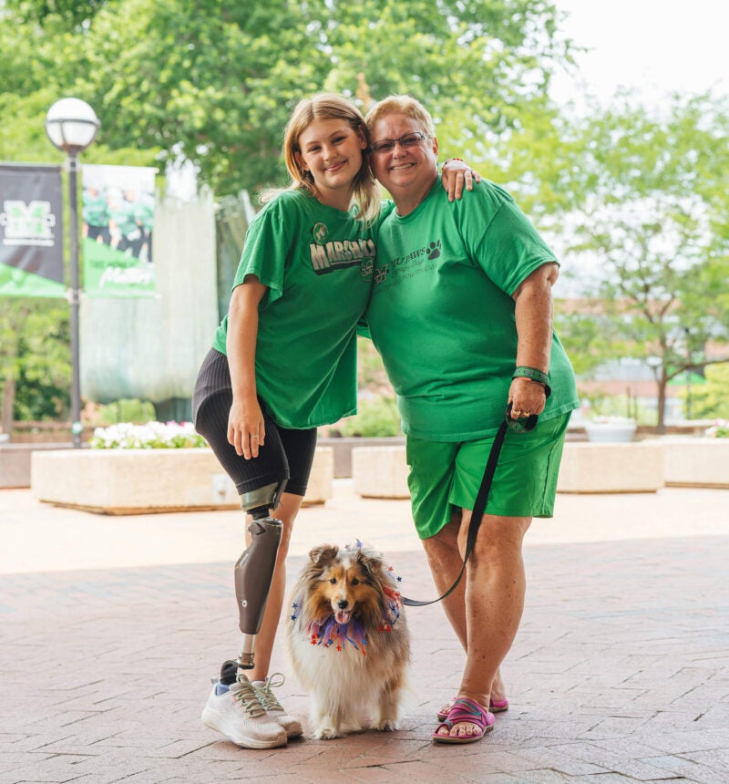 Isabella and Robin pose with therapy dog Bella during a Marshall University campus event.