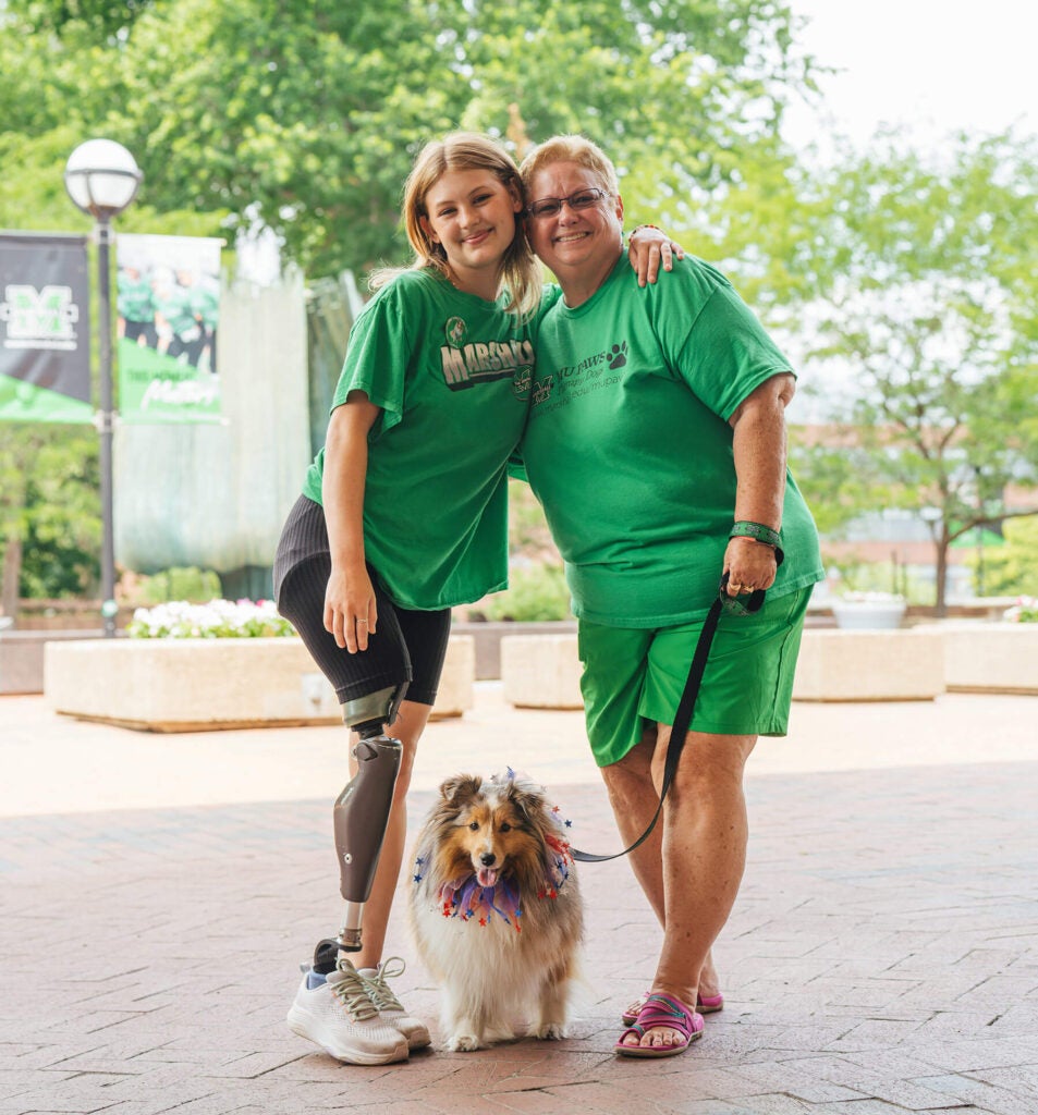 Isabella and Robin pose with therapy dog Bella during a Marshall University campus event.