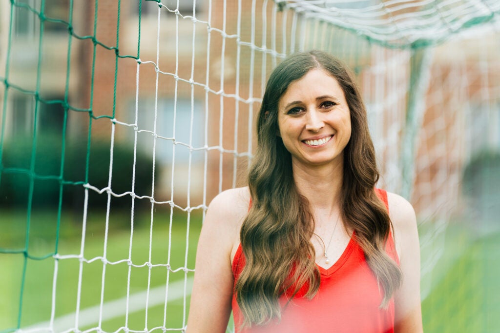 Skye Reymond stands in front of a soccer goal wearing a red shirt and smiling