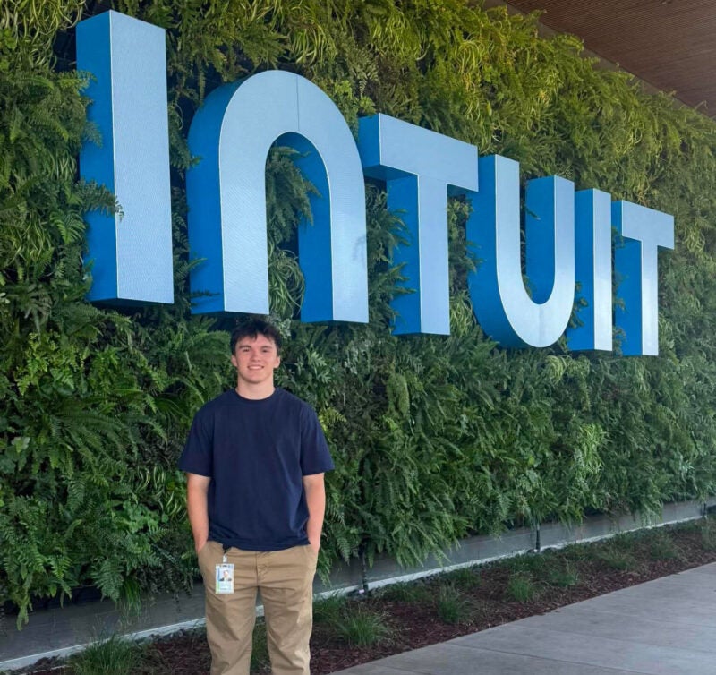 Brandon Anderson stands in front of an Intuit sign at their headquarters