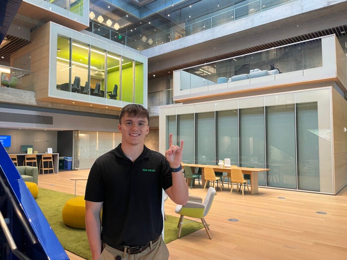 Brandon Anderson wears a Marshall polo shirt while standing in a common space in Intuit's office