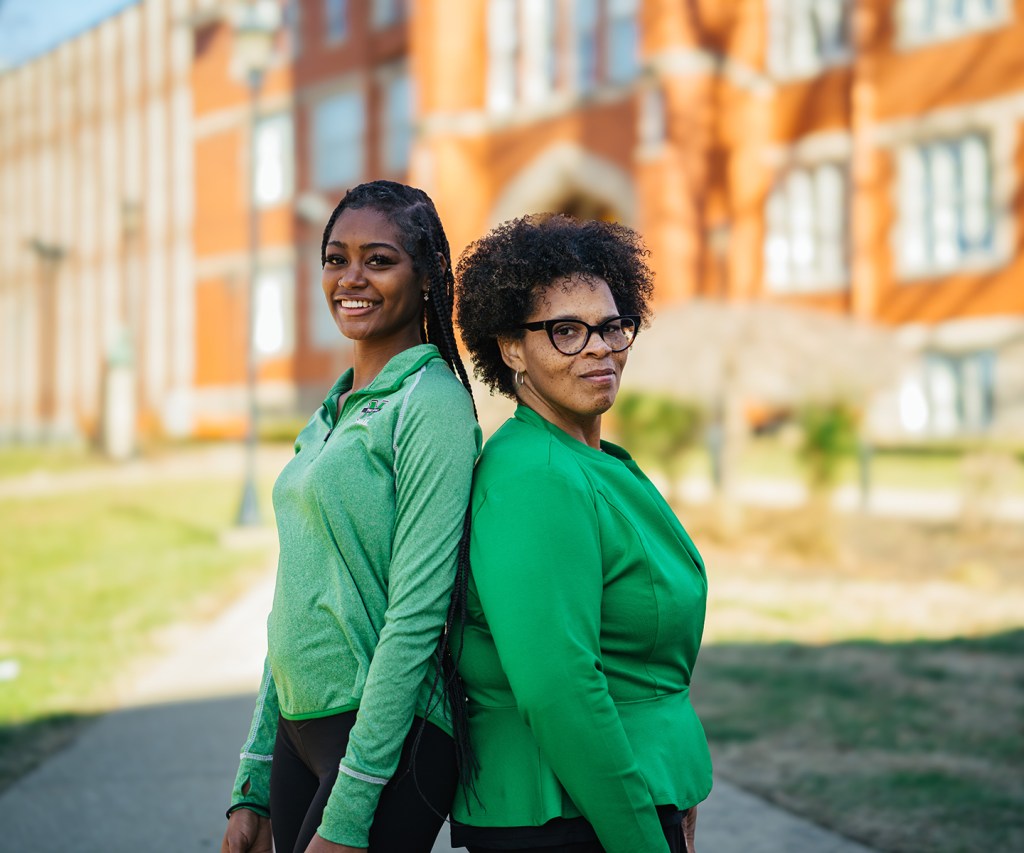 Kymora and Cassandra Woods stand back-to-back in front of Old Main at Marshall University