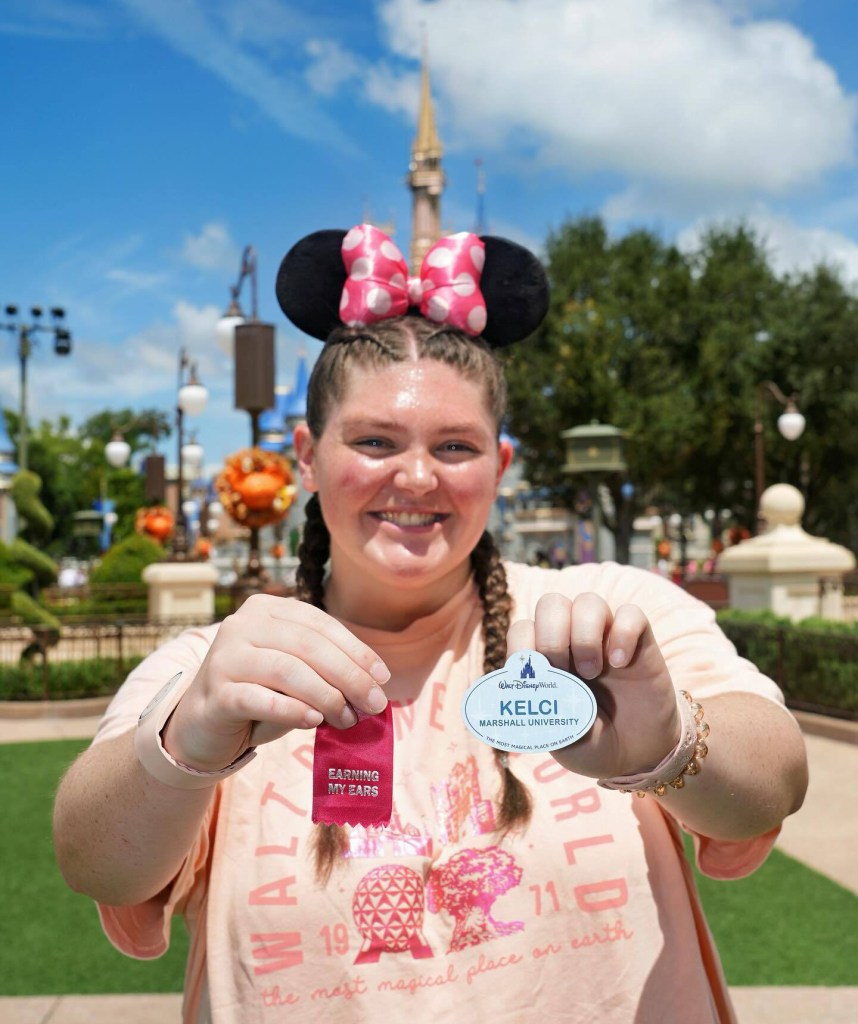 Kelci Armstead wears Mickey ears and holds her name tag and ribbon at Walt Disney World